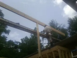 Carpenter setting a ridge beam over a new addition frame — Ice Dam Removal by Roofing Brothers in Rising City