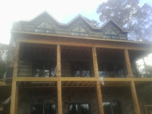 Dormers and porch framing on a large log home under construction — Roof Coating work by our crew in Rising City