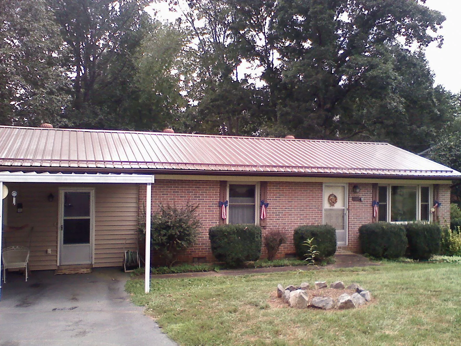 Bronze metal roof and carport on a brick ranch home — Roof Repair work by our crew in Rising City